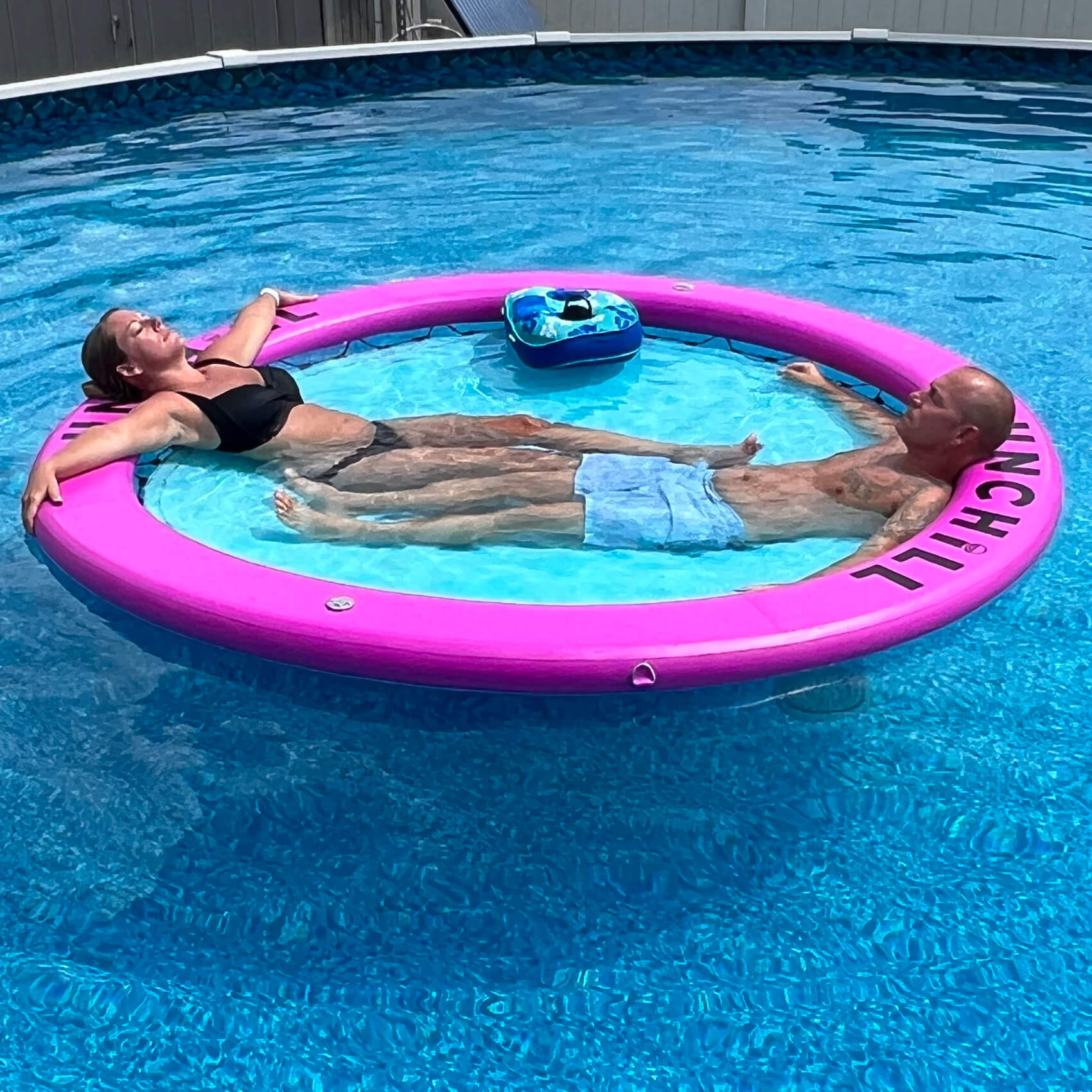 Two people lounging in a Blue Berry Sunchill water hammock in the pool.
