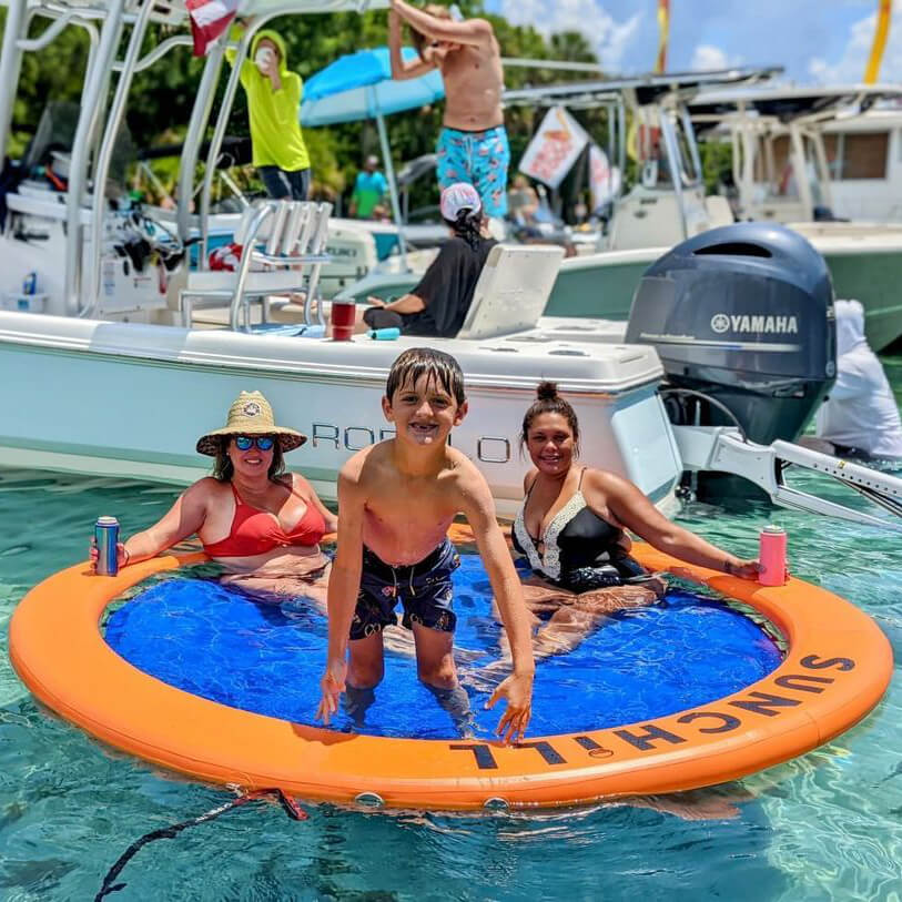 Family relaxing in the Coral Sea Sunchill lake float beside a boat.