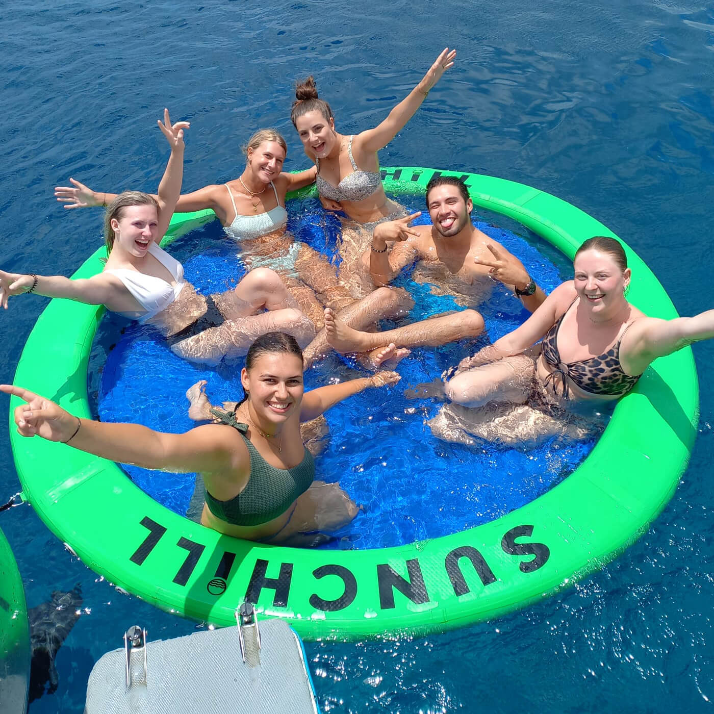 A group of friends smiling in a Sunchill lake float during a boat day.