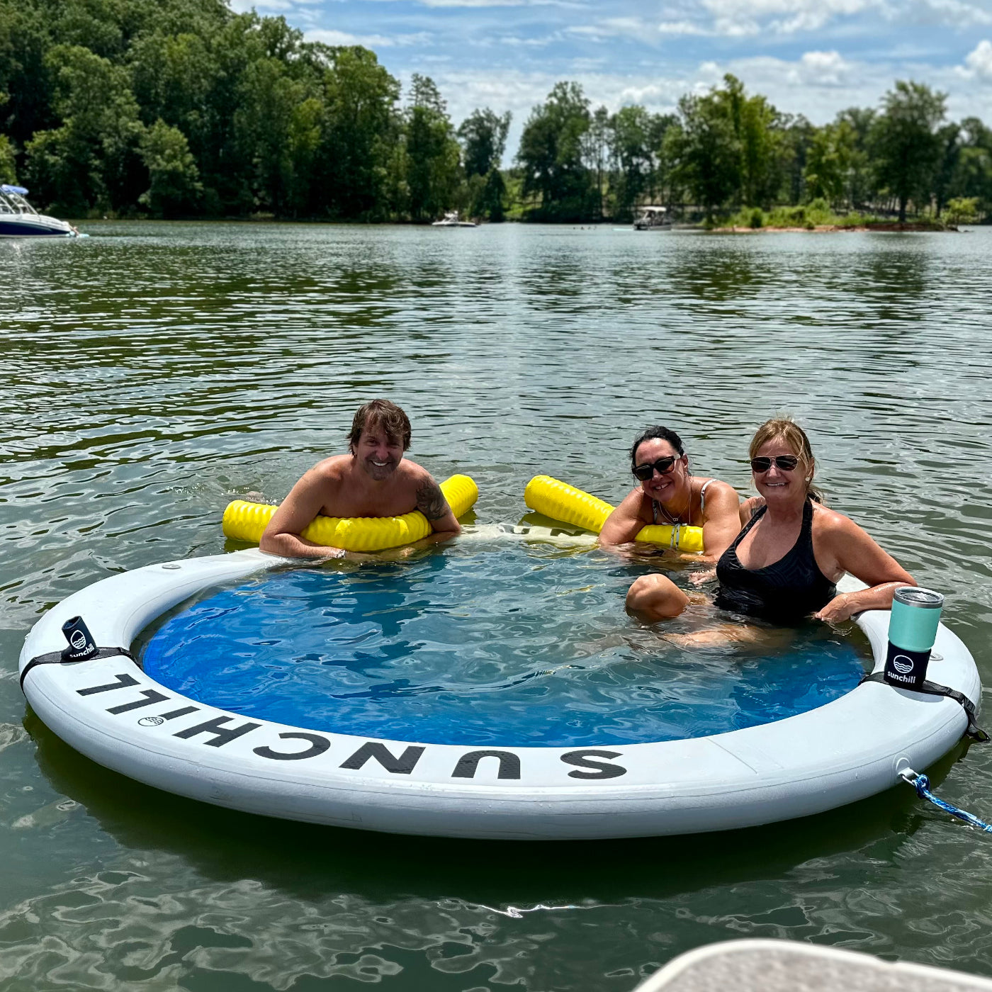 Three adults relaxing in the Silver Sunchill lake float with drink holders.