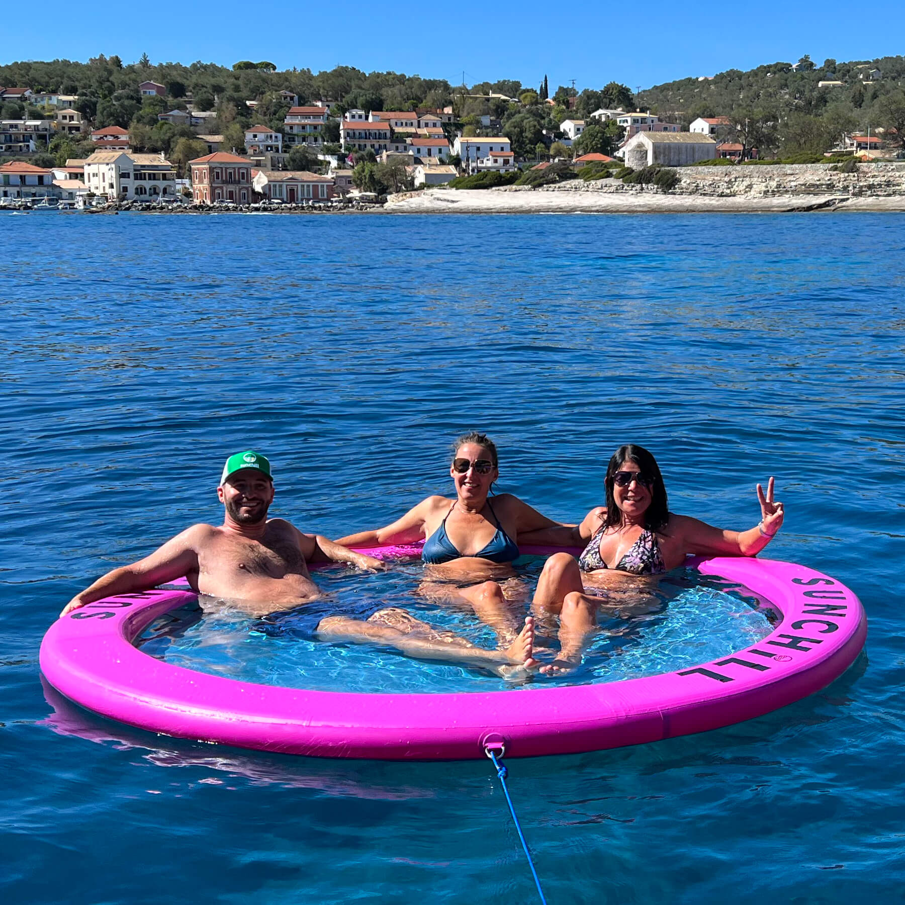 Three people relaxing in a Sunchill Water Hammock on the lake