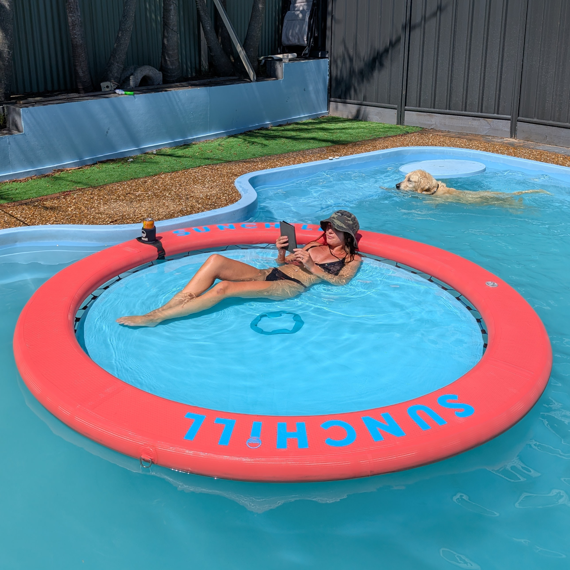 Woman and dog relaxing with a Coral Sea Sunchill float in the pool in Australia