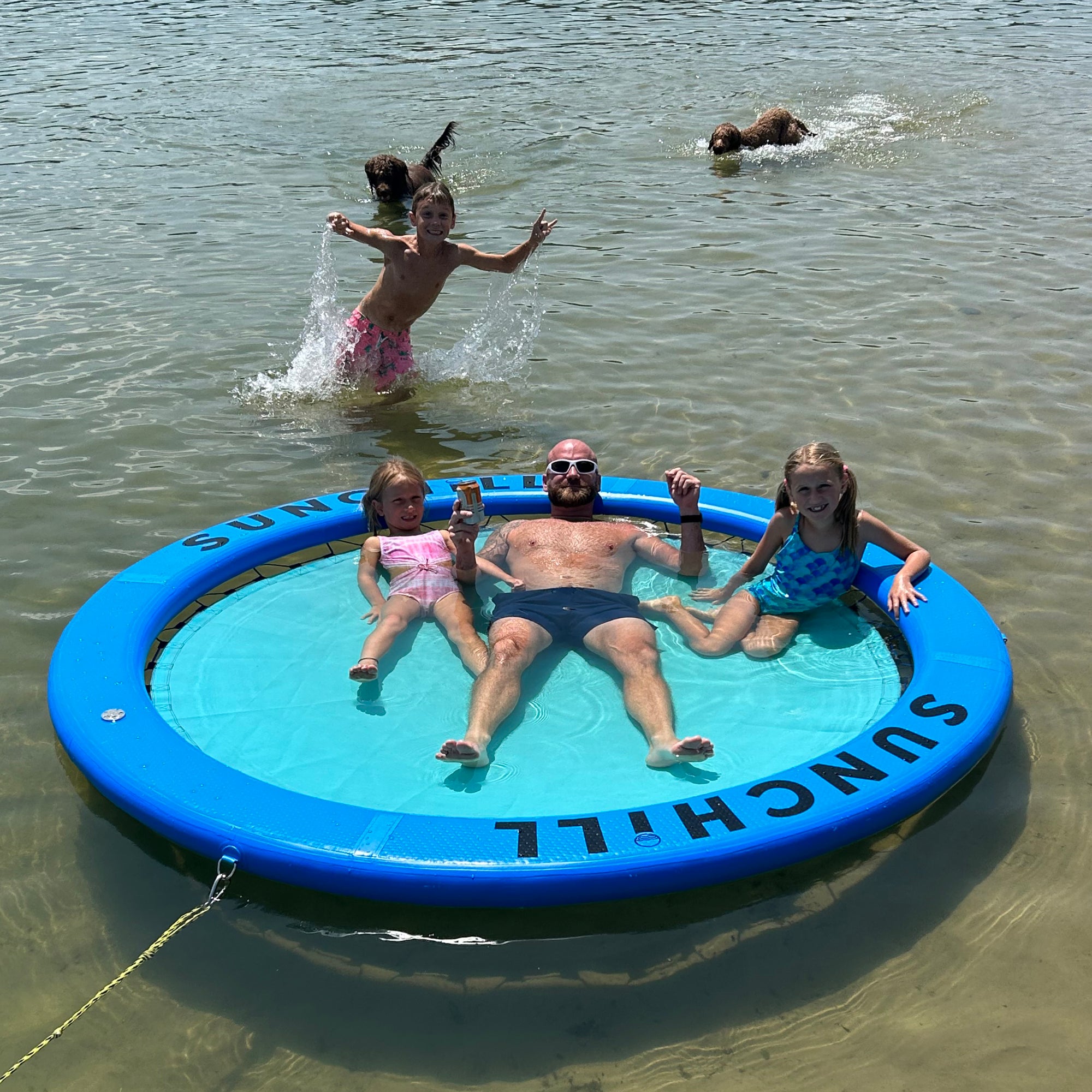 Family and dogs enjoying a Royal Blue Sunchill float in shallow water.