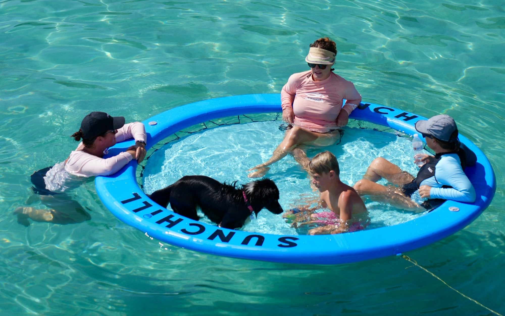 Family and dog gathered around a Royal Blue Sunchill float at the sandbar.