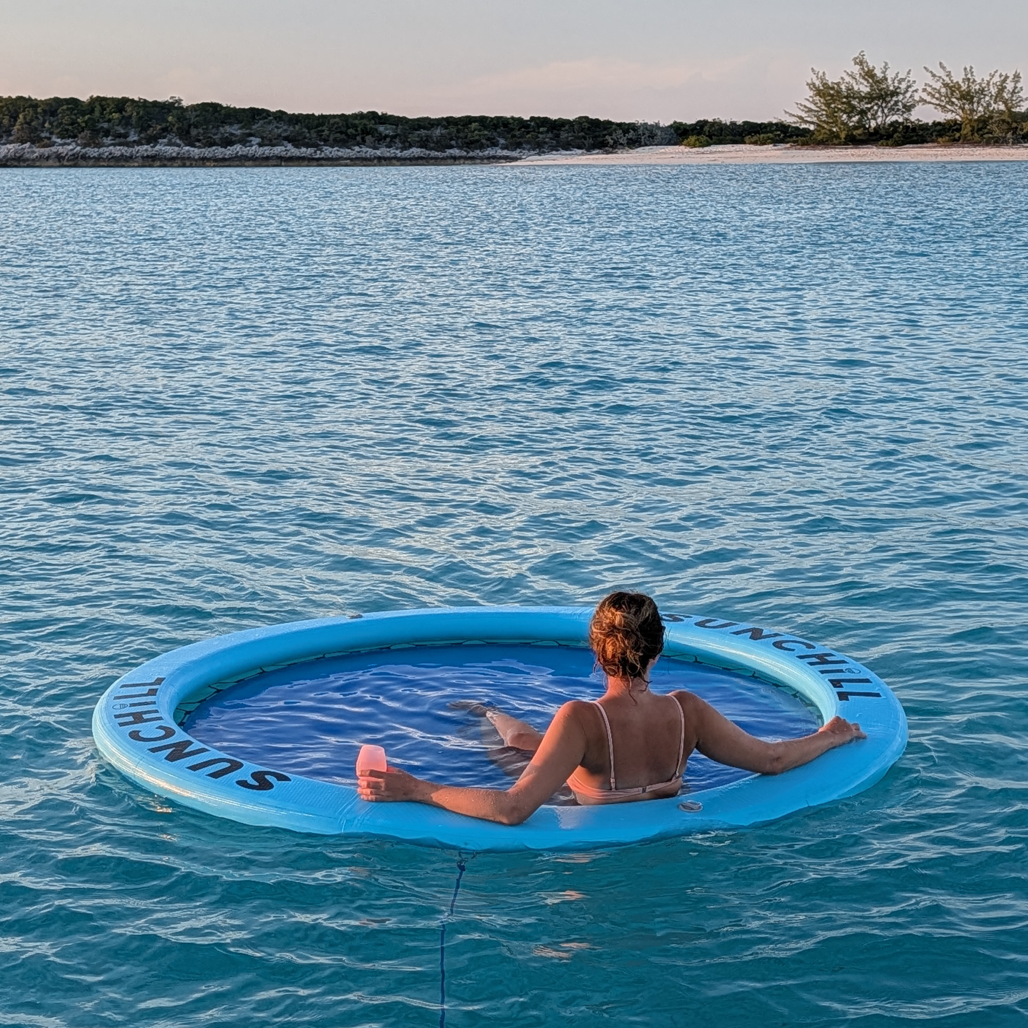 Woman relaxing in a Sky Blue Sunchill water hammock at sunset.