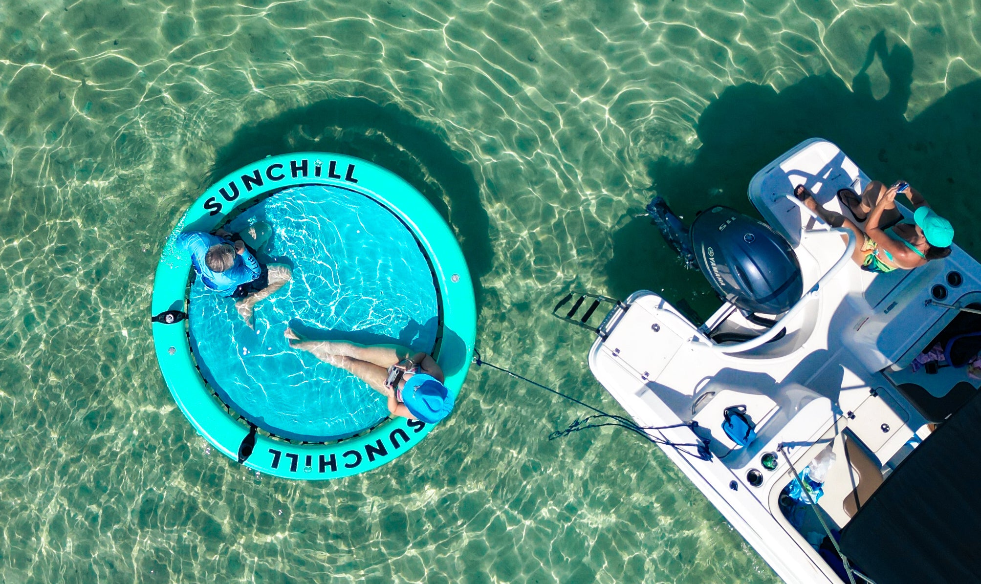 Drone view of a Spearmint Sunchill float beside a boat at beautiful sandbar with crystal clear water